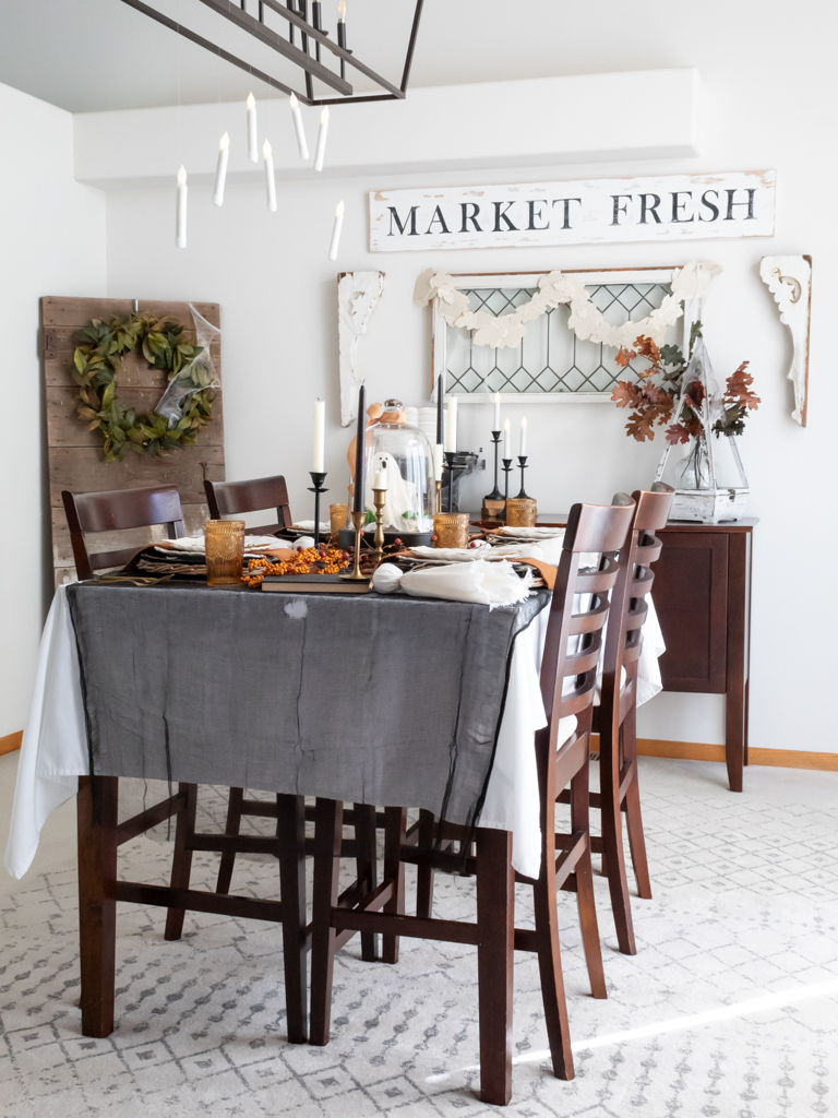 Black and Orange rustic Halloween tablescape set in the dining room with floating candles hanging from the chandelier overhead