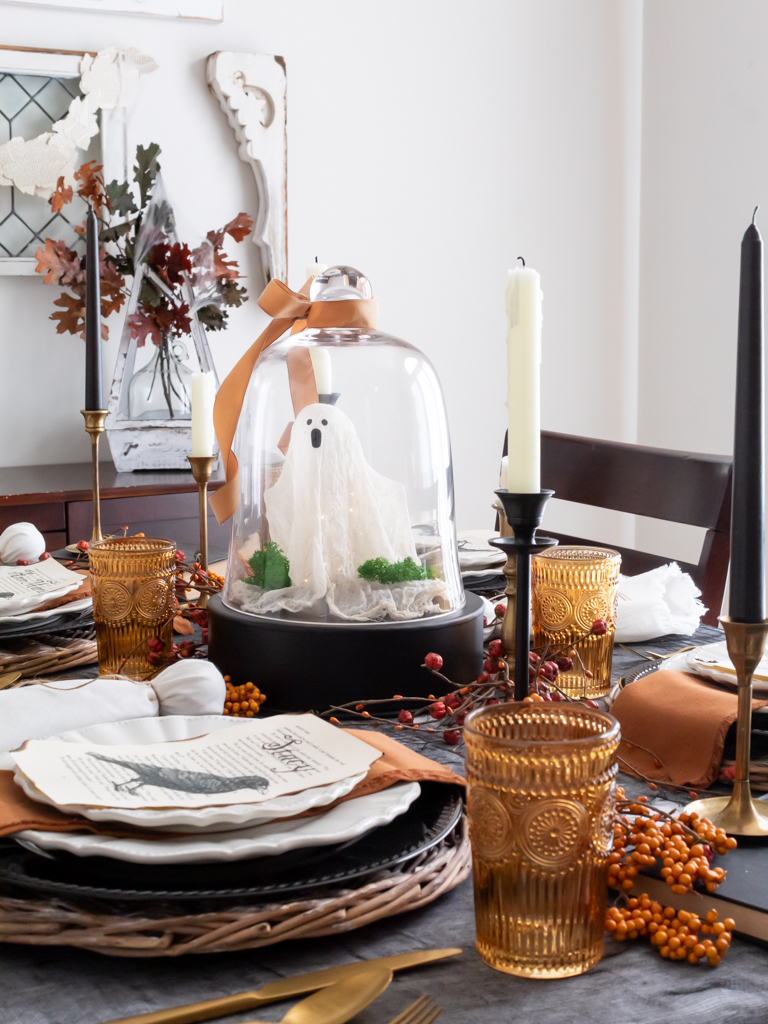 Ghost under a cloche centerpiece for a Halloween tablescape with orange and black decor