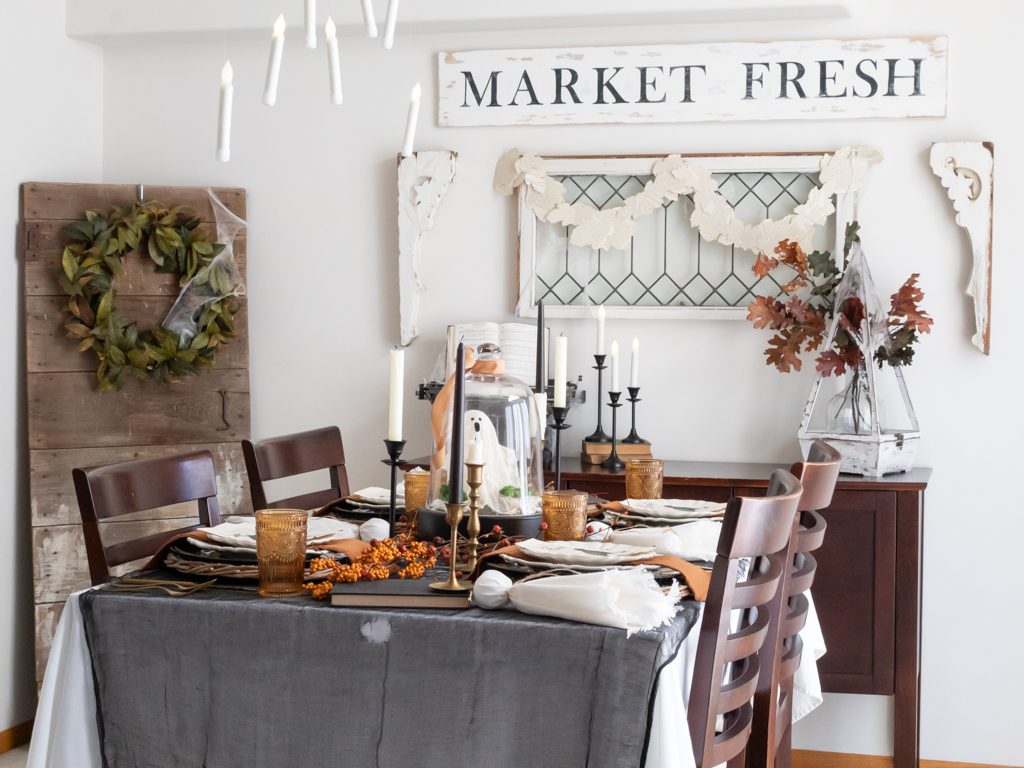 Halloween tablescape with rust orange and black decor a ghost centerpiece and hanging magic candles above the table