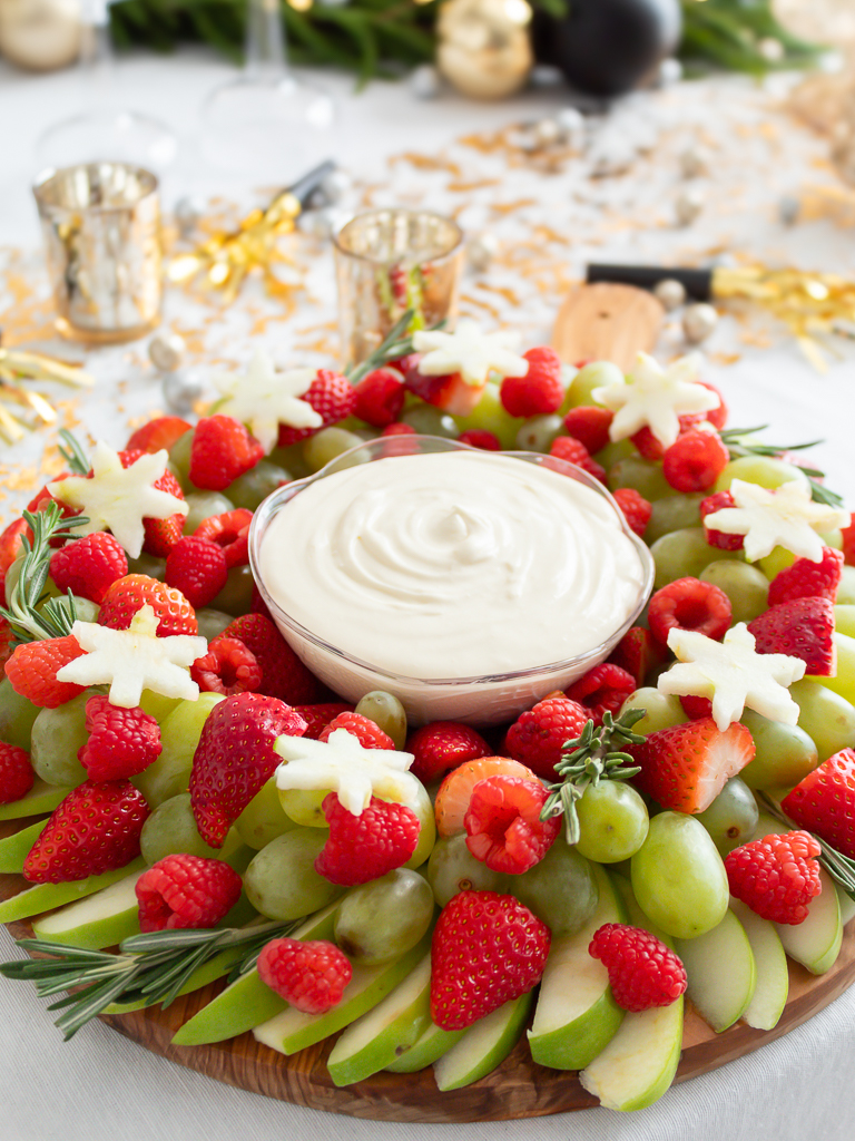 Red and green Christmas fruit wreath made with strawberries, green apples, and grapes served with creamy fruit dip