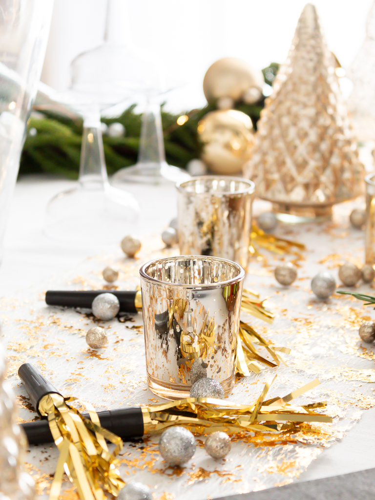 Up close view of festive New Year's party favors and noise makers used as decorations on a black and gold tablescape set for a New Year's Eve Party. 