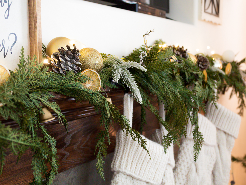 Neutral and rustic Christmas mantel with greenery and ornaments