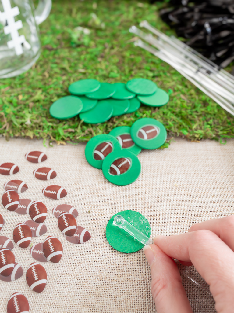 Gluing football decorations onto drink stir sticks