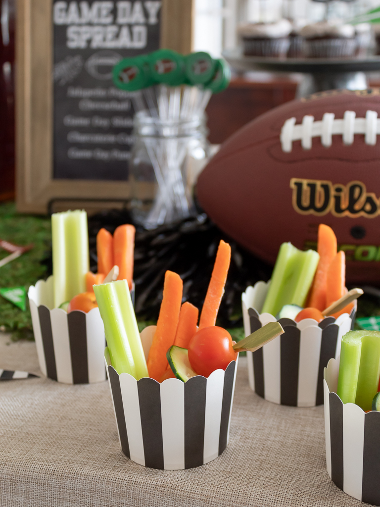 Charcuterie cups for a football party in black and white cupcake cups with herb dip, carros, cerelry, cherry tomatoes and cucumbers