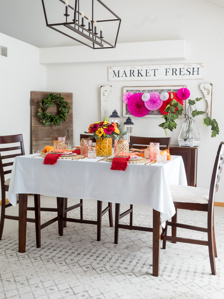 Dining Room Styled for a Chinese New Year Dinner Party with Bambo Lanterns, Woven Placemat with Red and Coral Linens and Brightly Colored Flowers with Sliced Oranges