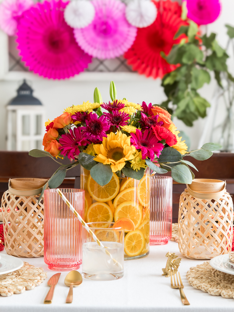 Chinese New Year Tablecape with Bambo Lanterns, Paper Fans, and Brightly Colored Flowers with Sliced Oranges