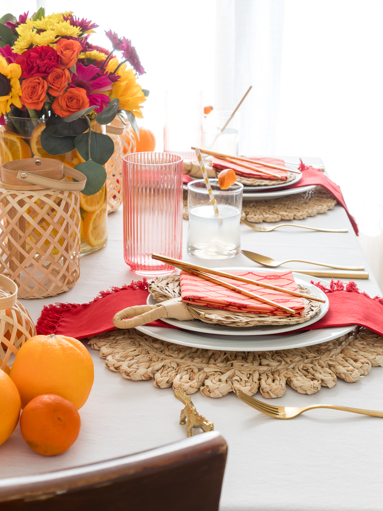 Chinese New Year place setting with bamboo fan, gold chopsticks, red napkins, and gold dragon.