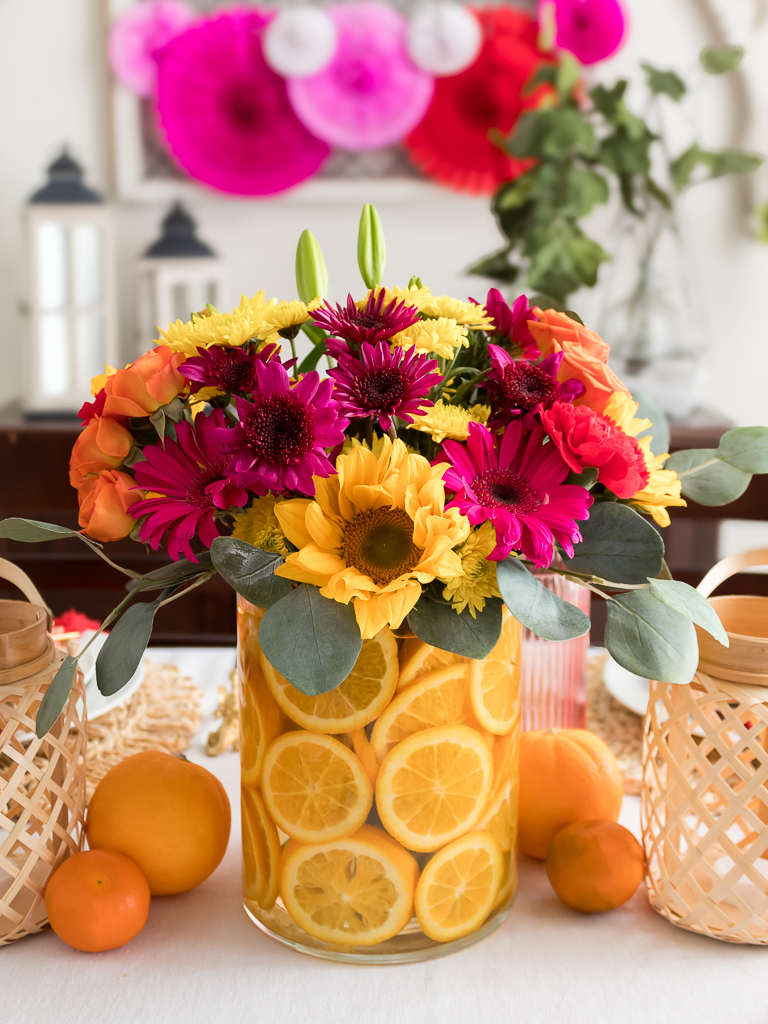 DIY centerpiece made with colorful flowers in a vase with sliced oranges 