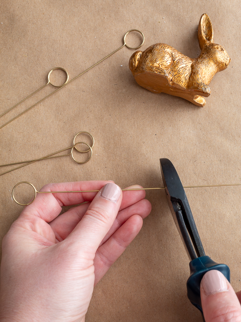 Woman's Hand Cutting Thin Gold Place Card Rings and Small Gold Bunny to Make DIY Easter Napkin Ring Holders