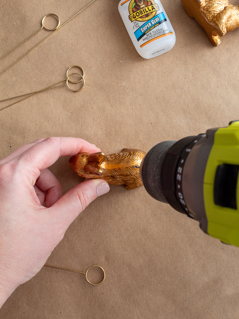 Woman's Hand Drilling into Small Gold Bunny for DIY Easter Place Card Holders