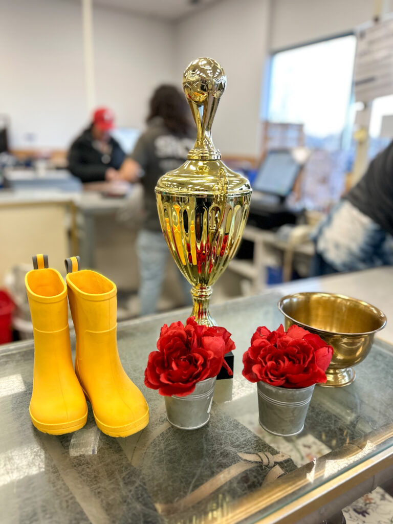 Thrifted decor items including kids yellow rain boots, gold tropy, brass bowl, and small tins with red silk flowers