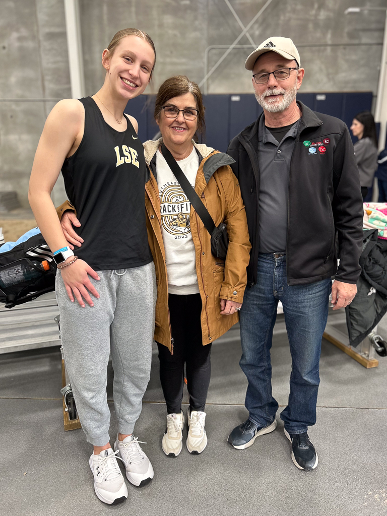 Grandaughter posing with her grandparents at a track meet