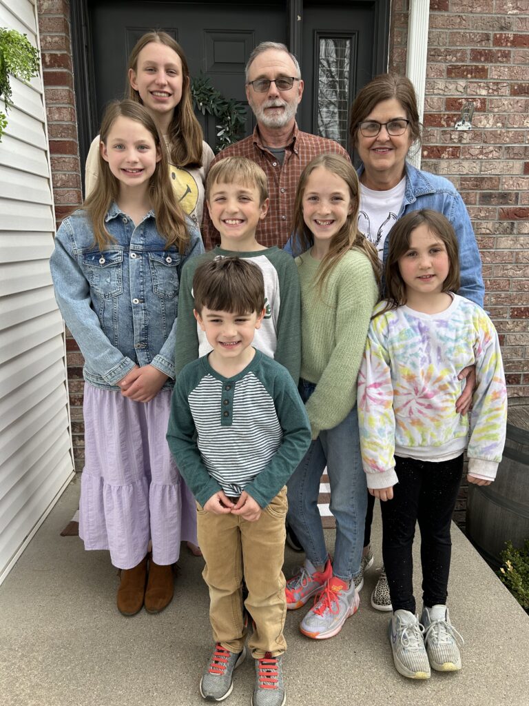 grandparents with six grandkids smiling and posing for a picture on Easter