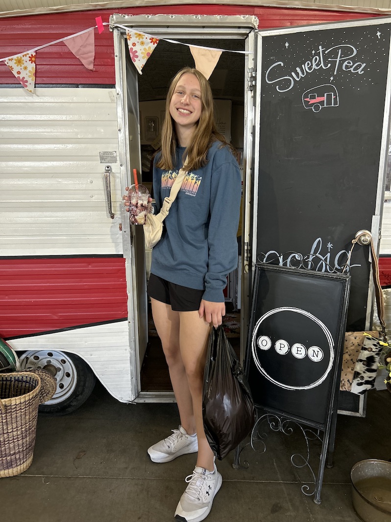 girl standing in front of vintage trailer with blended coffee 