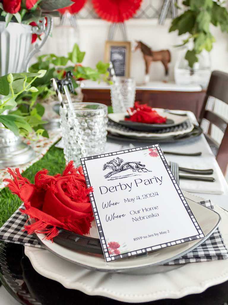 Close-up view of free printable red adn black Kentucky Derby party invitation styled on a table set for a horse-themed party