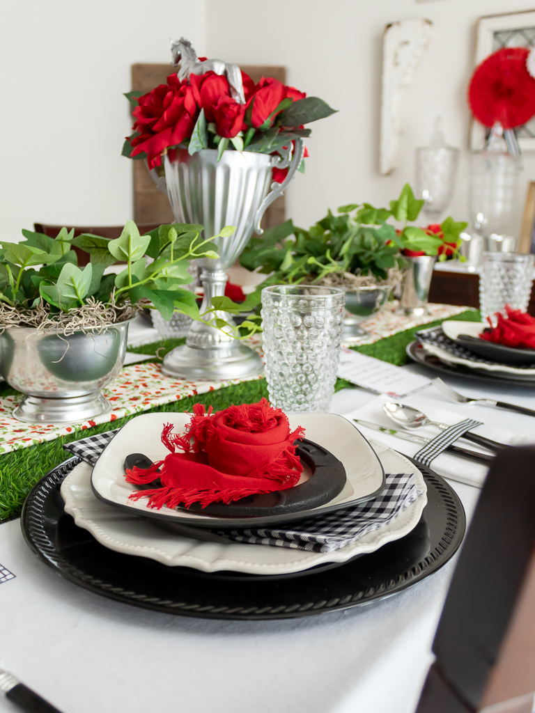 Red cloth napkin folded in the shape of ar ose set ona plate for a red and black Kentucky Derby-themed tablescape