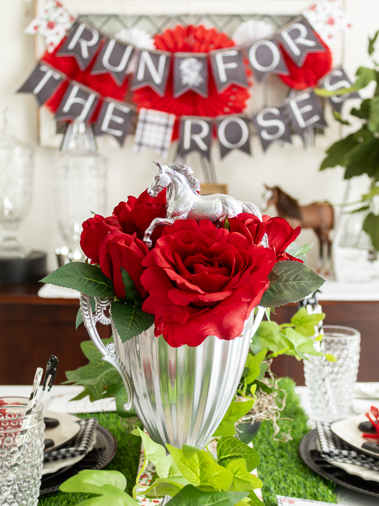 Close up view of thrifted trophy turned into a DIY horse trophy centerpiece with red roses for a Kentucky Derby tablescape and party