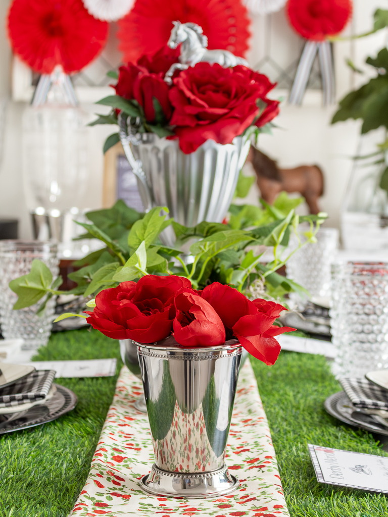 Close up of mint julep cup filled with red roses and tulips for a Kentucky Derby party tablescape centerpiece