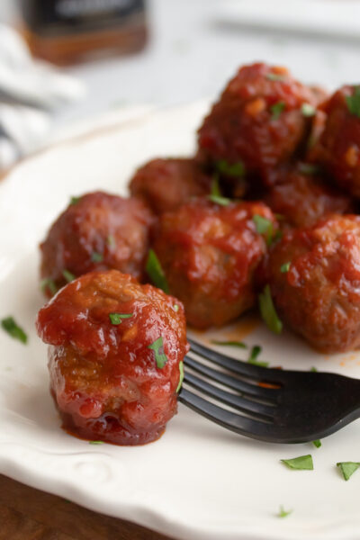 Crockpot Bourbon Meatballs plated on display with one on a fork