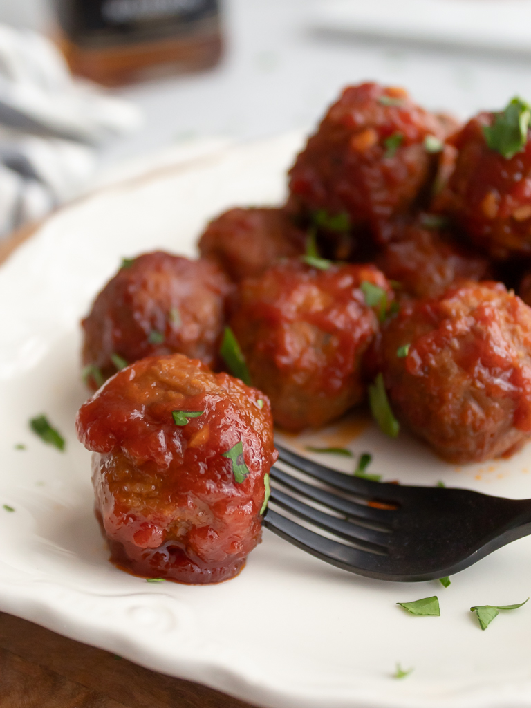 Crockpot Bourbon Meatballs plated on display with one on a fork