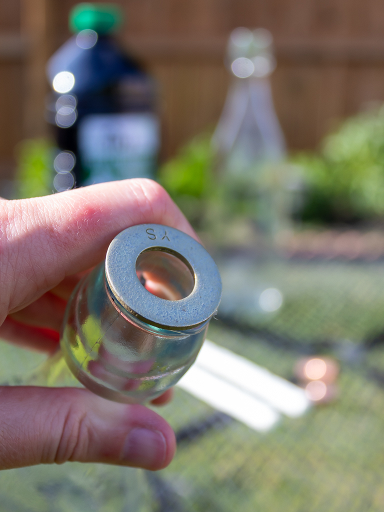 glueing a washer on a glass bottle to make tabletop tiki torches