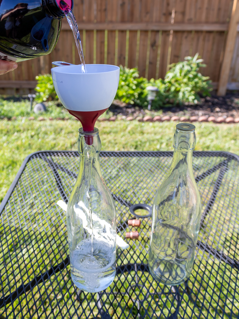 Pouring citronella fuel in DIY bottle tabletop torches