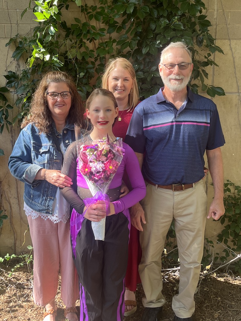 smiling family with grandparents, daughter, and granddaughter after dance recital 