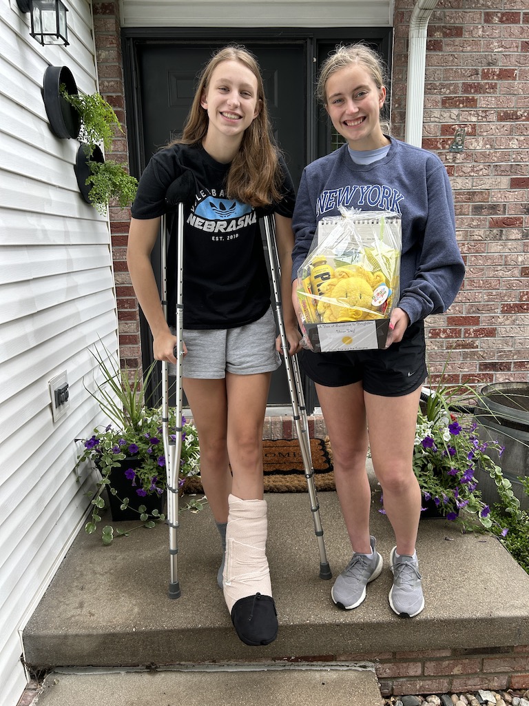 two teammates posing and smiling with a get well-basket for the injured player