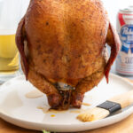 Smoked Beer Can Chicken resting on plate still sitting on the can of beer