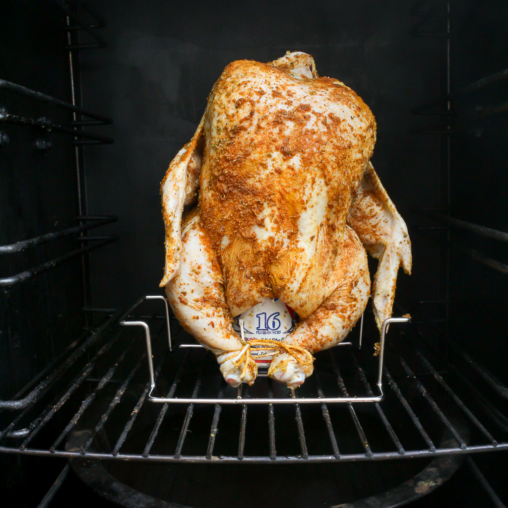 Raw beer can chicken in the smoker ready to be cooked