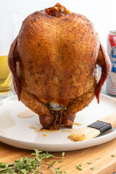 Smoked Beer Can Chicken resting on plate still sitting on the can of beer