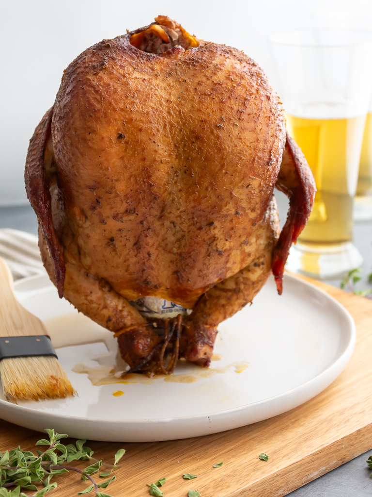 Smoked beer ban chicken resting on a plate with pilsner beer glasses in the background