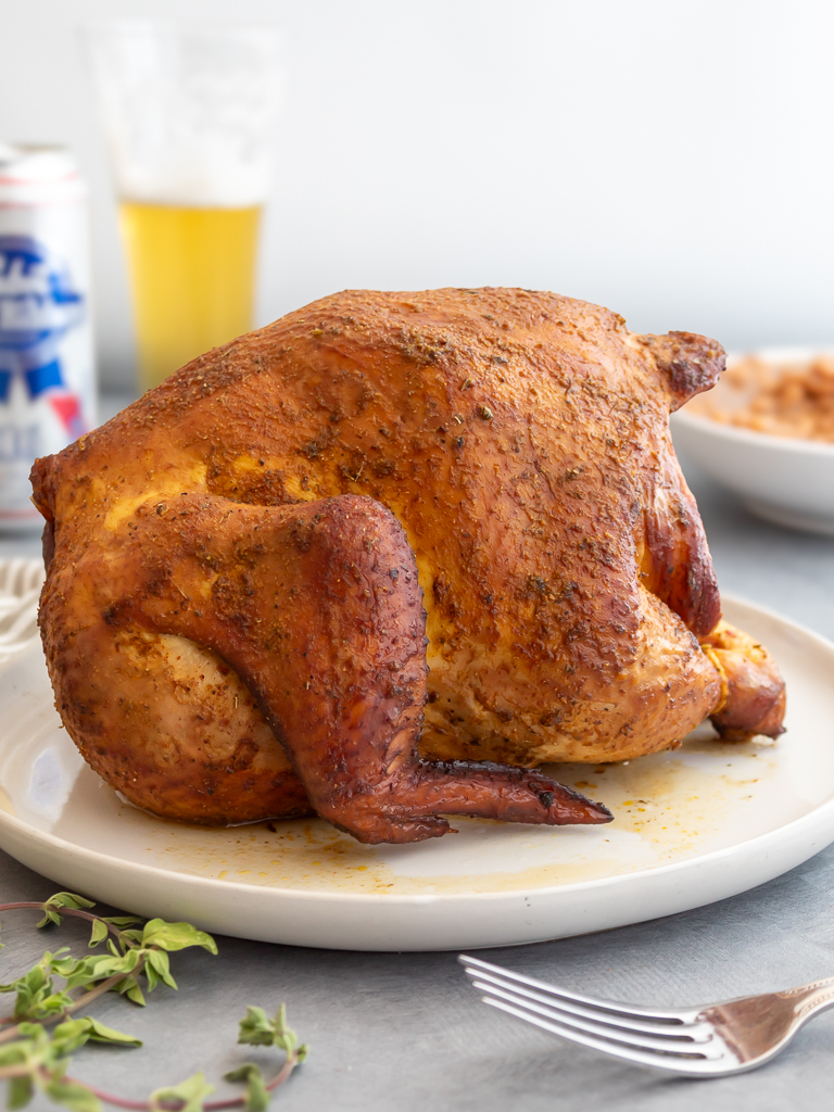 Whole smoked beer can chicken  resting on a place 