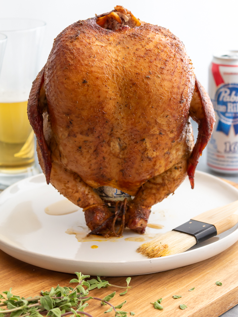 Smoked Beer Can Chicken resting on plate still sitting on the can of beer