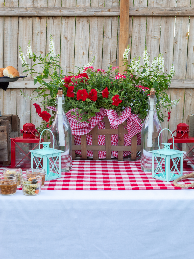 A picnic basket filled with red and white summer flowers for a cookout or BBQ centerpiece