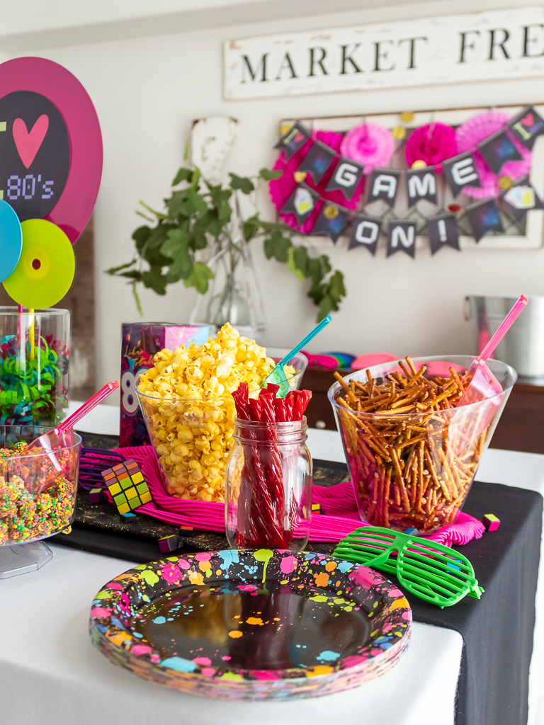 Bowls filled with pretzles and popcorn on the food buffet for an 80s themed game night party