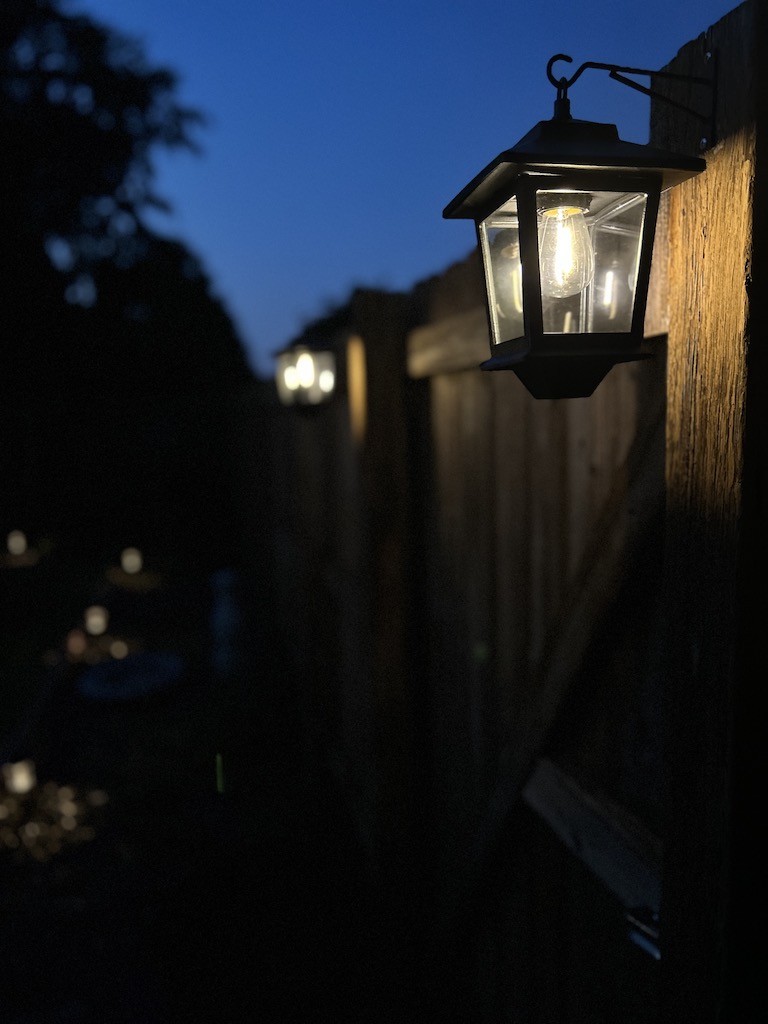 Solar lanterns lit up a night hanging on a garden fence