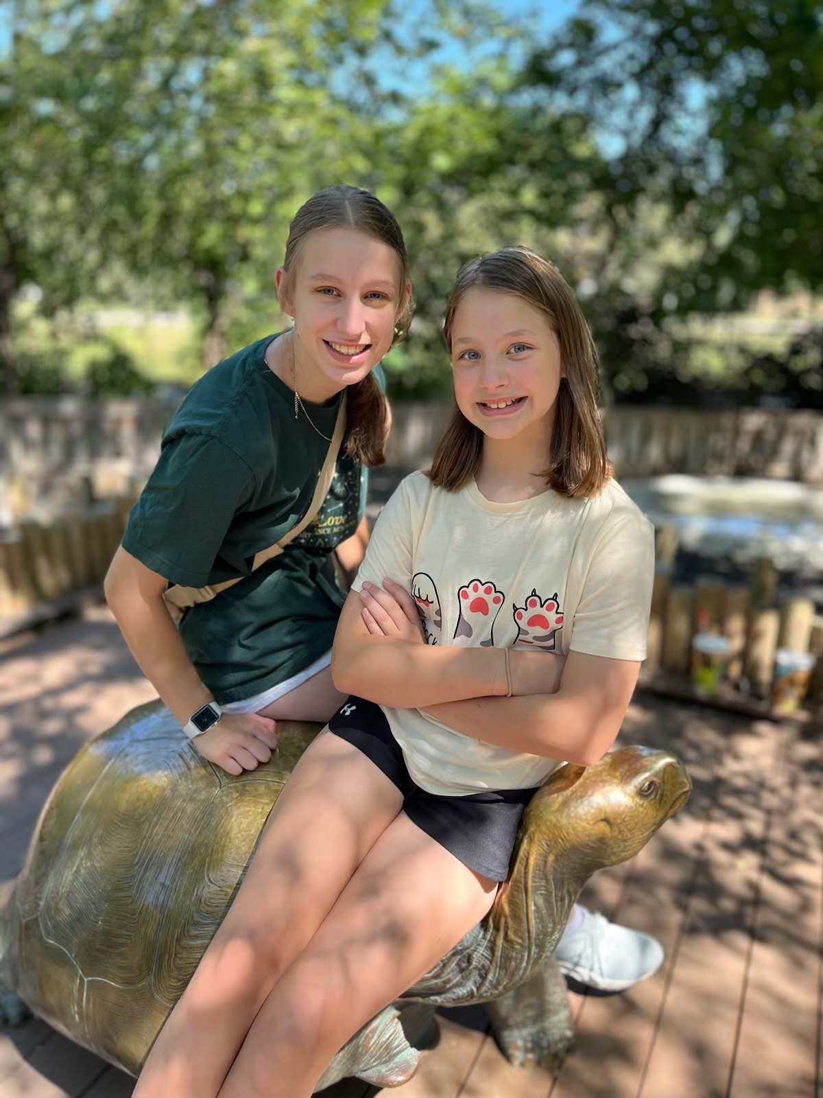 Two sisters smiling and posting for a picutre at the zoo