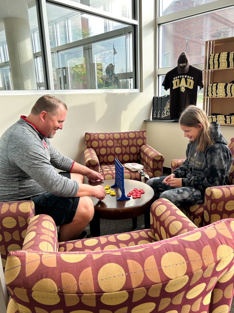 father and daughter playing a game of connect 4 