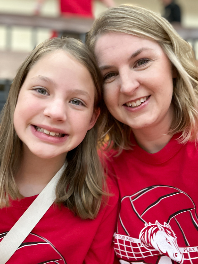 mother and daughter posing in the crowd at a volleyball game