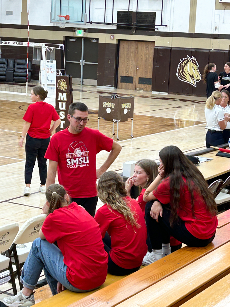 a coach and potential atheletes visiting prior to a college volleyball game 