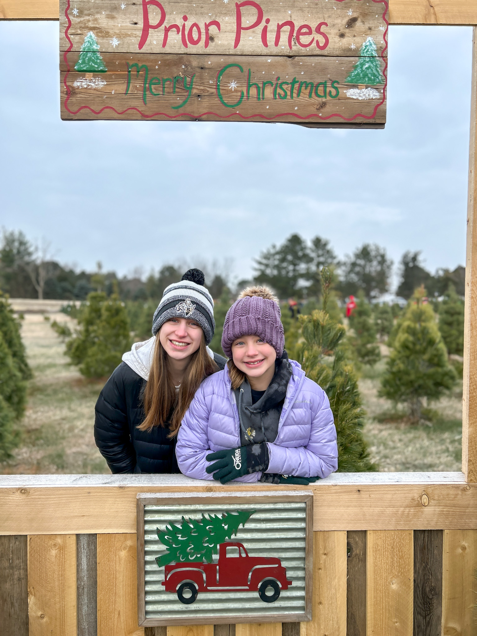 Two girls smiling at a Christmas tree farm