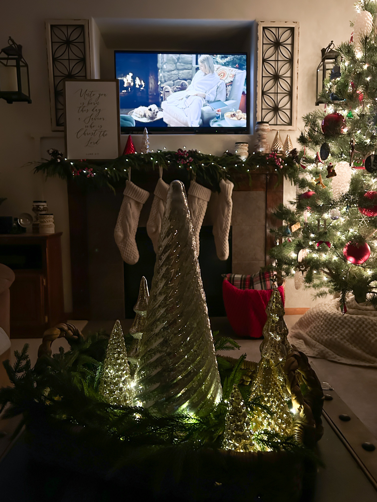 Christmas tree decorated in living room and a decorated fireplace lit up with lights at nighttime