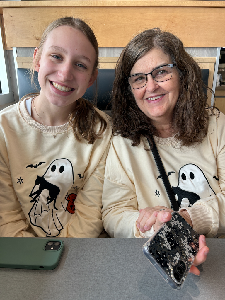 smiling grandmother and granddaughter in matching Halloween sweatshirts