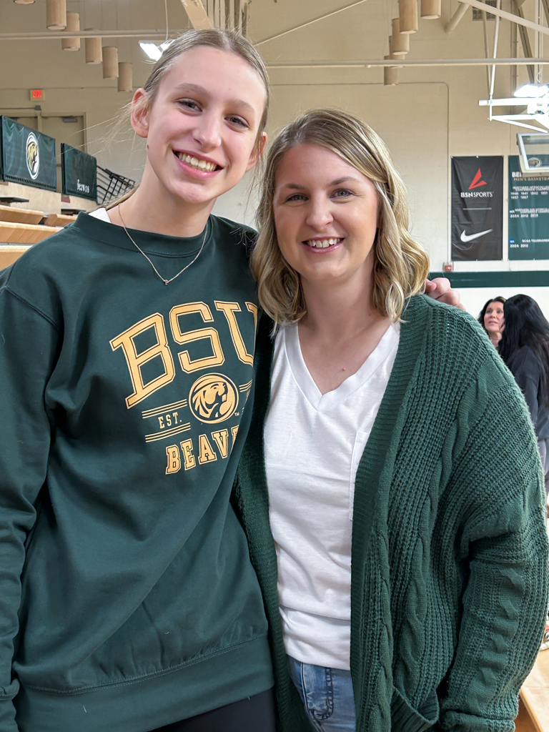 Mother and daughter smiling and posing for a photo at a volleyball game