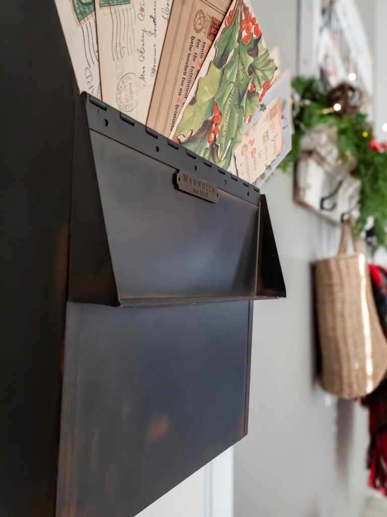 Decorative black square mailbox hanging on a closet door filled with vintage Christmas postcards