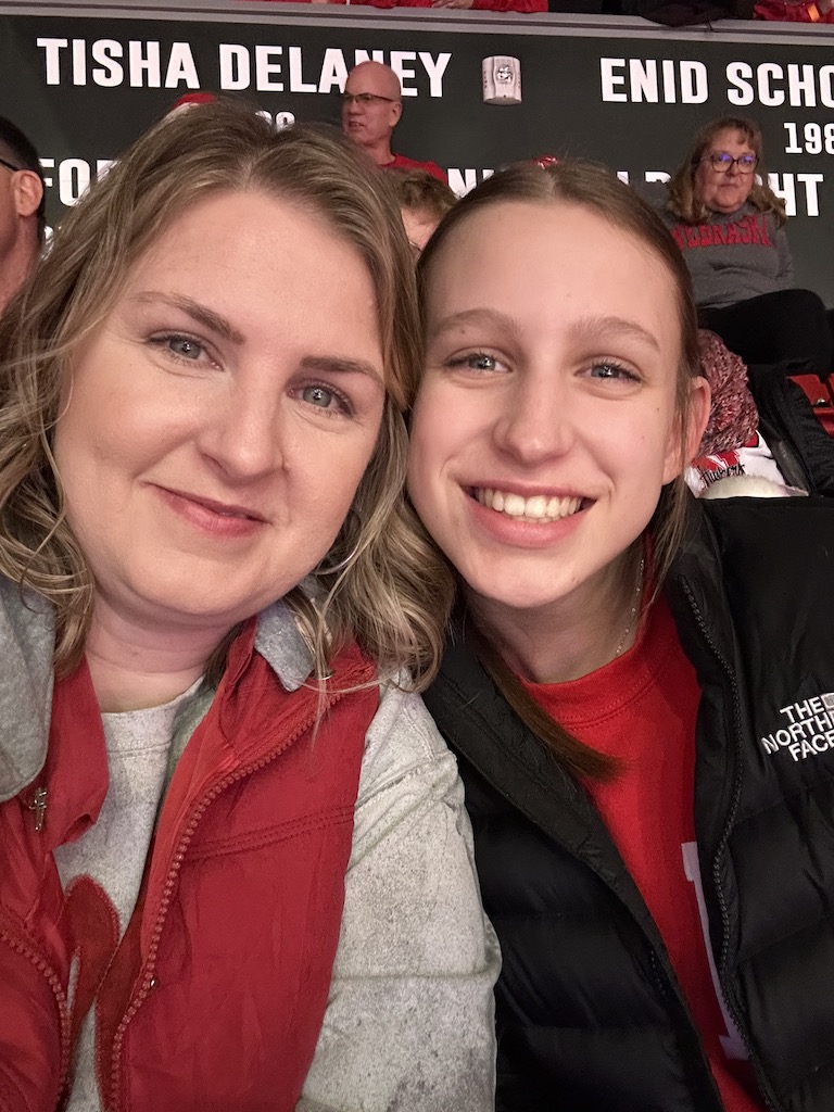 Mom and daughter posign and smiling at a college volleyball game