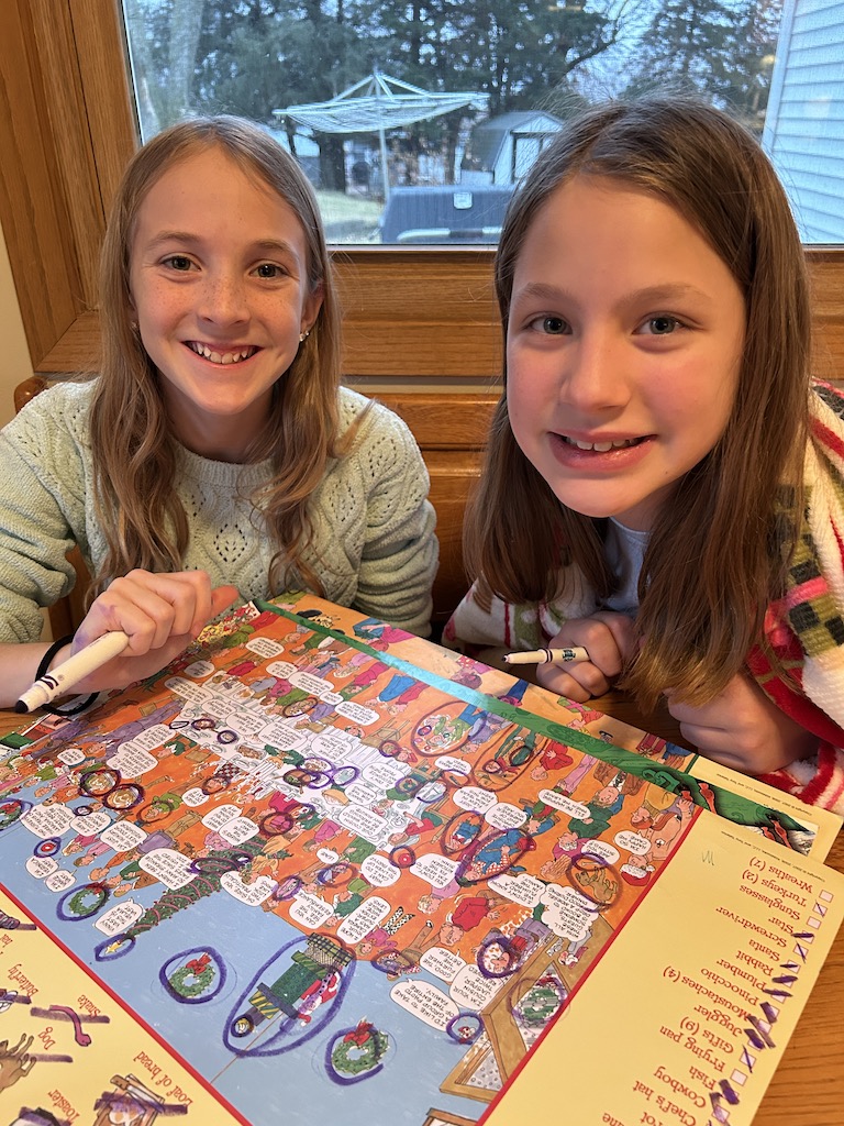 Cousins sitting at a table in the kitchen doing a Christmas wordsearch puzzle