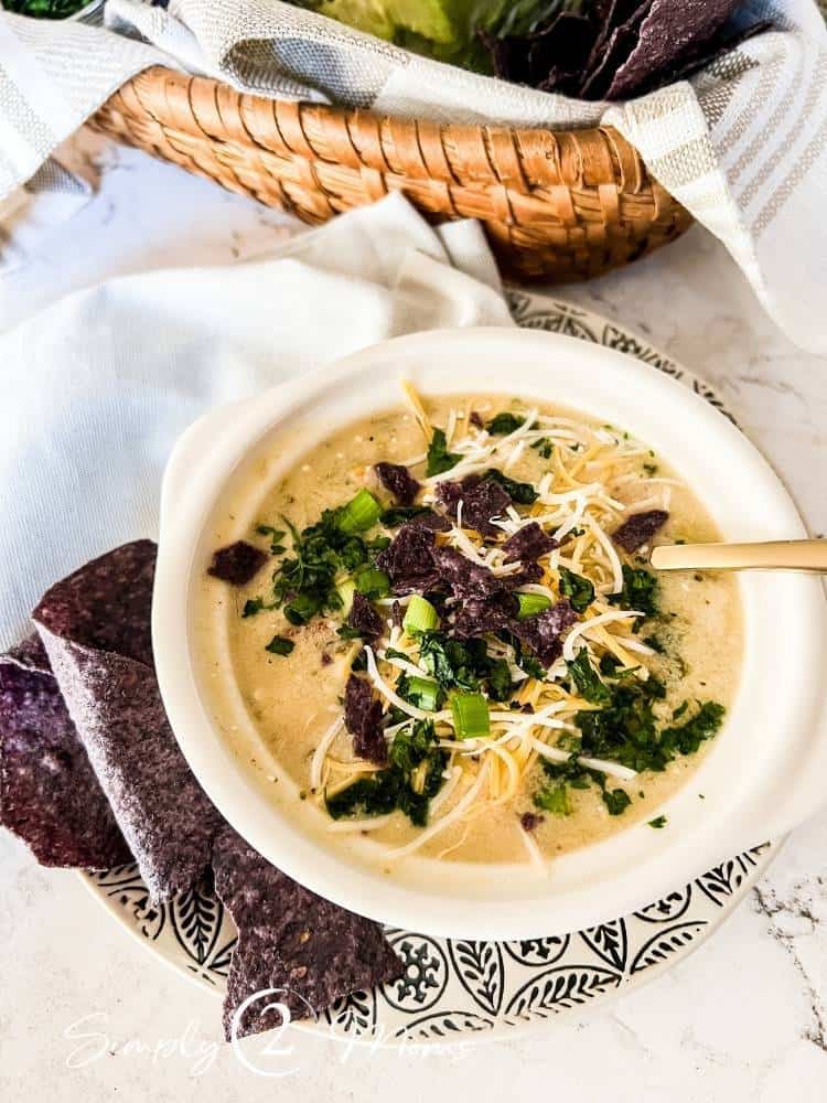 Bowl of white chicken chili topped  with cheese and tortilla chips from Simply 2 Moms