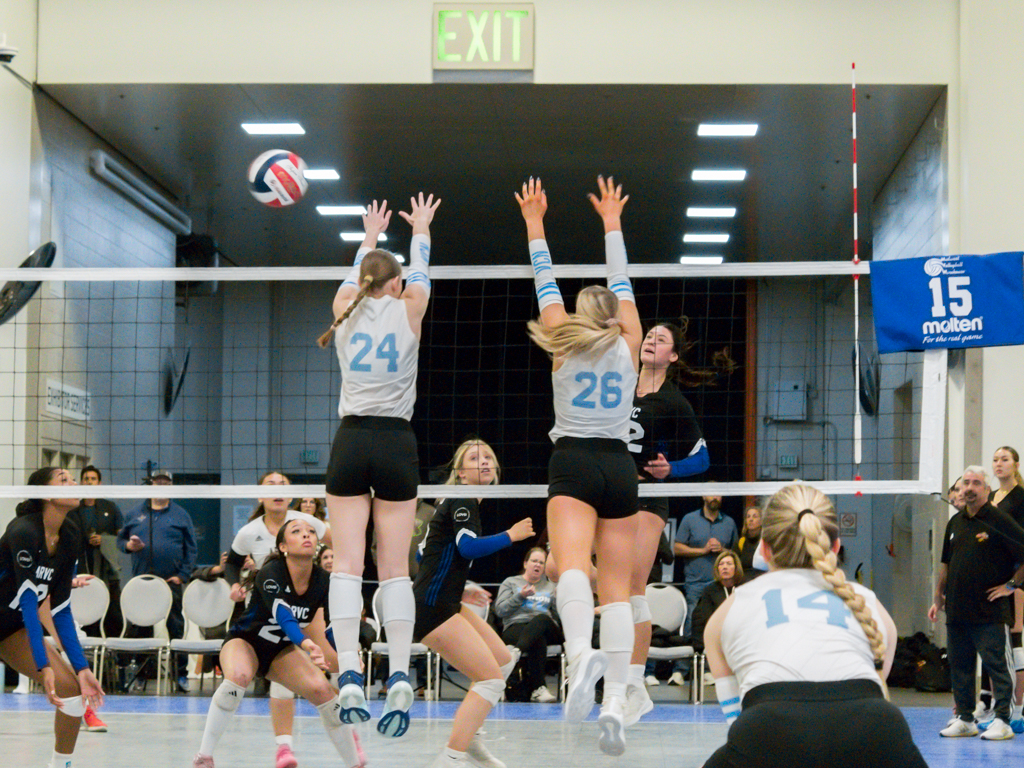 Two volleyball players going up for a block 